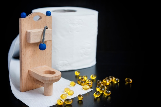 Houten speelgoedtoilet, capsules en papier op zwart