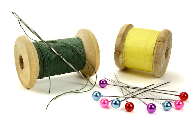 Foto houten spoelen met draadspelden en naald om op wit te naaien