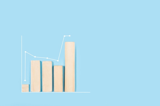 Houten staven in een financiële grafische vorm op een lichtblauwe achtergrond met kopieerruimte