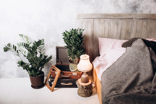 Houten stoel aan kaptafel in roze pastel slaapkamer interieur met gouden lamp naast bed