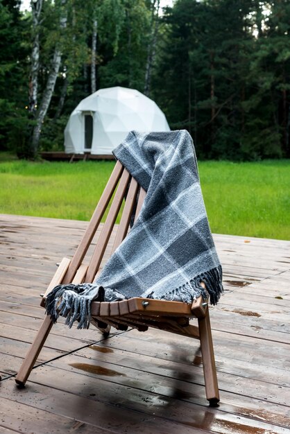 Houten stoel met wollen deken en glampingtent Houten buitenstoel op houten platform