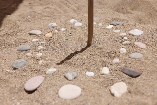 Houten stok en kiezelstenen op zand die tijd door schaduw tonen