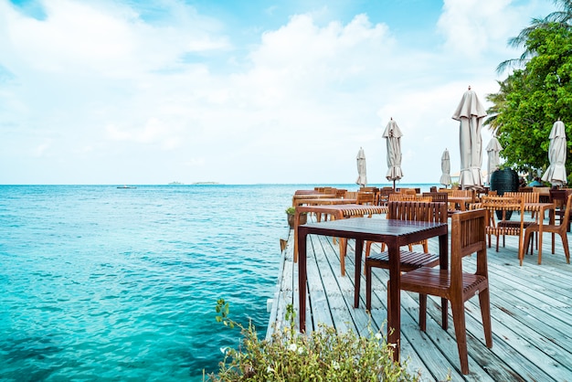 Foto houten tafel en stoel met uitzicht op zee achtergrond in maldiven