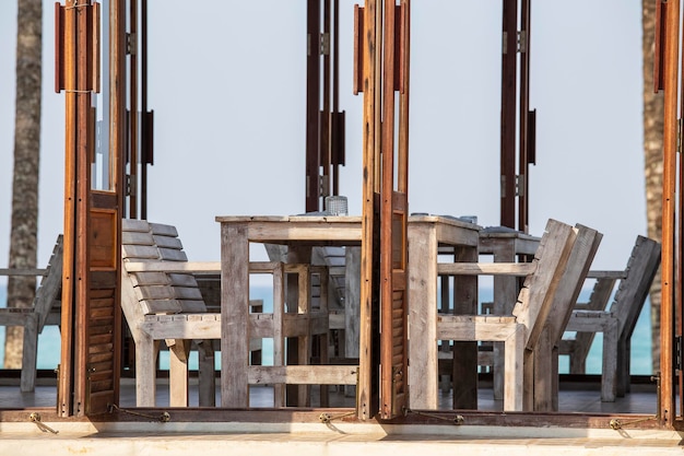 Houten tafel en stoelen in leeg strandcafé naast zee Thailand