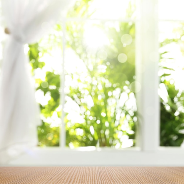 Houten tafel en uitzicht door raam op tuin lente