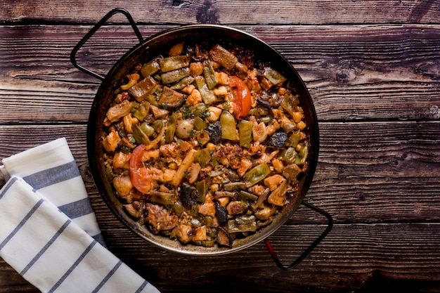 Houten tafel geserveerd, traditionele paella. Traditioneel eten om te delen, smaken van de wereld.