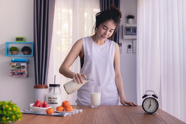 houten tafel met jonge Aziatische vrouw gieten melk