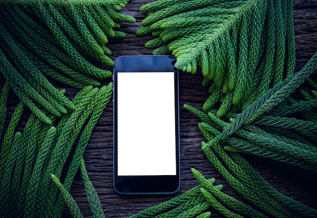 Houten tafel met leeg scherm op smartphone over bladeren grenskader.