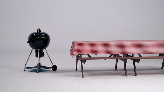 Houten tafel met rode servetdoek en zwarte BBQ-kachel en witte achtergrond in studio