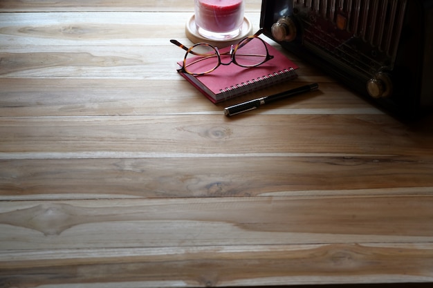 Houten tafel met vintage radio, rode notitie boek en kopie ruimte