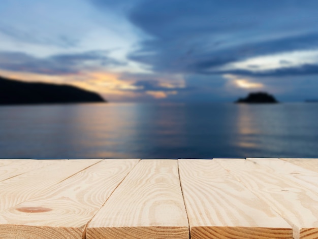 Houten tafel voor abstract wazig met het oog op de lichte zonsondergang over de zee-achtergrond.