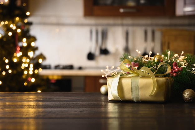 Houten tafelblad met gouden cadeau-kerstversiering en wazig moderne keuken voor weergave of montage van uw producten.