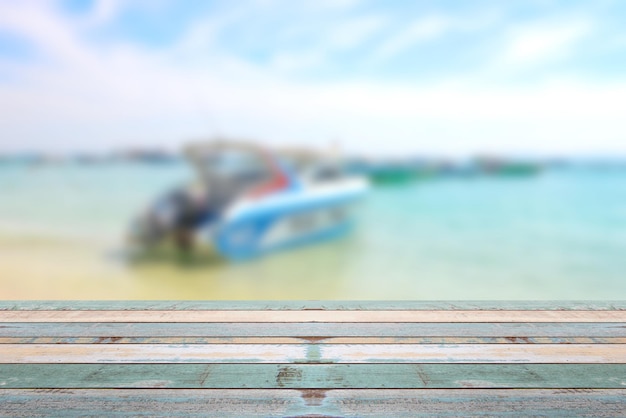 Houten tafelblad met vage boot op het strand zomervakantie achtergrondconcept kan worden gebruikt voor het weergeven of monteren van uw producten