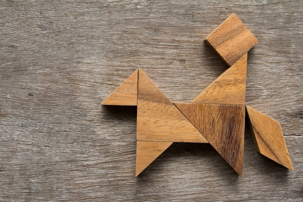 Houten tangram als mens berijdt de paardvorm op oude houten achtergrond