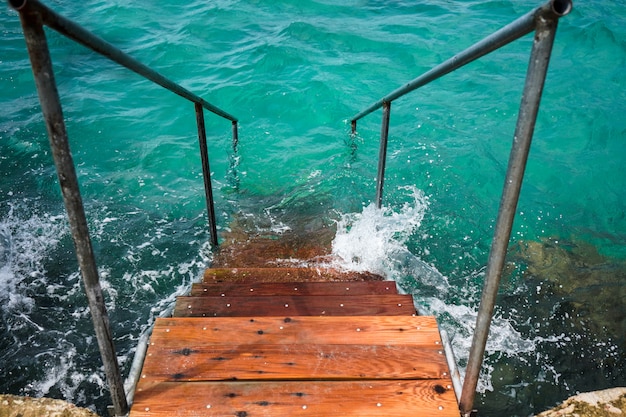 Houten trap naar het kristal turquoise water in de Ionische Zee, Saranda, Albanië