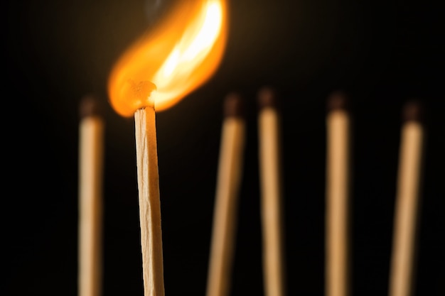 houten verlichte lucifers die op een zwarte achtergrond staan