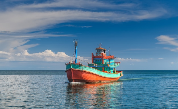 Houten vissersboot in de zee met buitenzonverlichting en bewolkte hemel