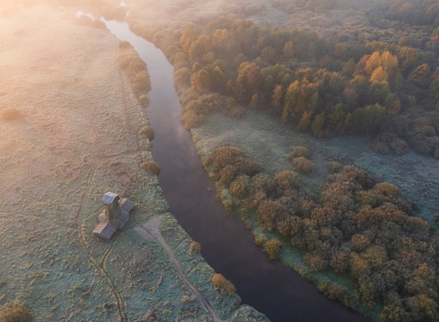 Houten windmolen aan de rivier op het platteland bij zonsopgang en mist in de herfst, in de ochtend van de eerste vorst. bovenaanzicht vanuit de drone