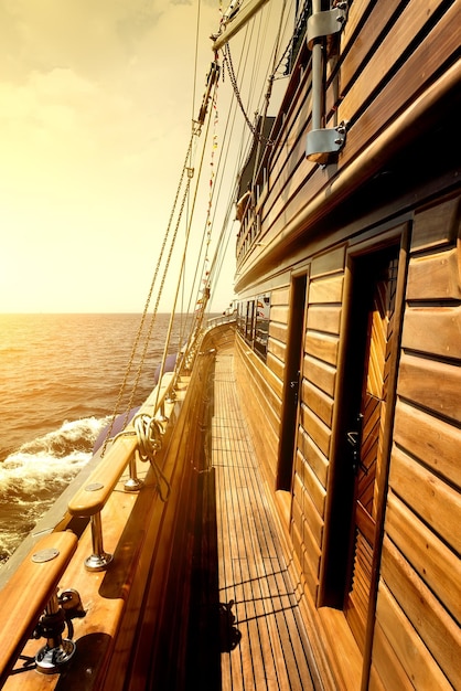 Houten zeilboot in zee bij de heldere zonsopgang