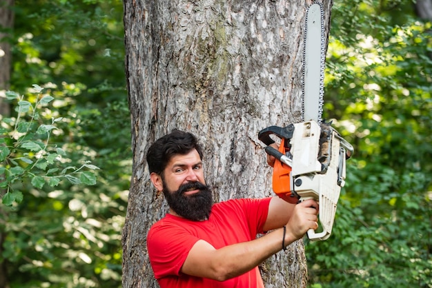 Houthakker werknemer wandelen in het bos met kettingzaag stijlvolle jongeman poseren als houthakker lumbe...