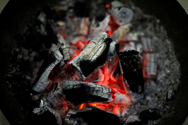 Houtskool verbranden in een ijzeren kachel voor huisverwarming. rood gebrande houtskool en as om de kamer te verwarmen.