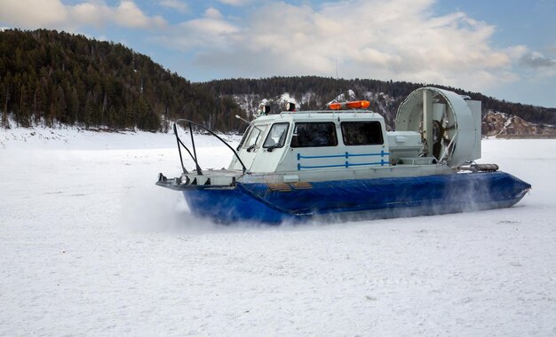 A hovercraft glides over the surface of a frozen river Winter tourism