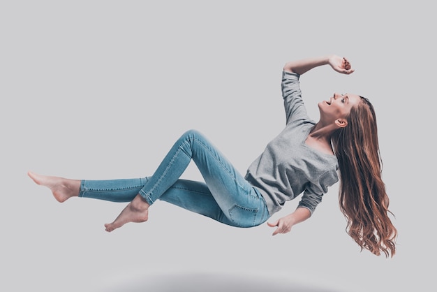 Hovering in air. Full length studio shot of attractive young woman hovering in air and smiling