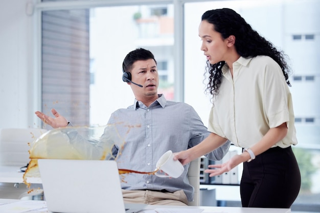 how clumsy can you be shot of a businesswoman spilling a cup of coffee over a colleagues desk in a call centre