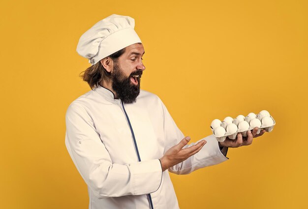 How to cook eggs concept of housekeeping mature bearded man wear chef hat male cook ready for preparing food brutal hipster in apron going to be cooking meal time for eating happy baking