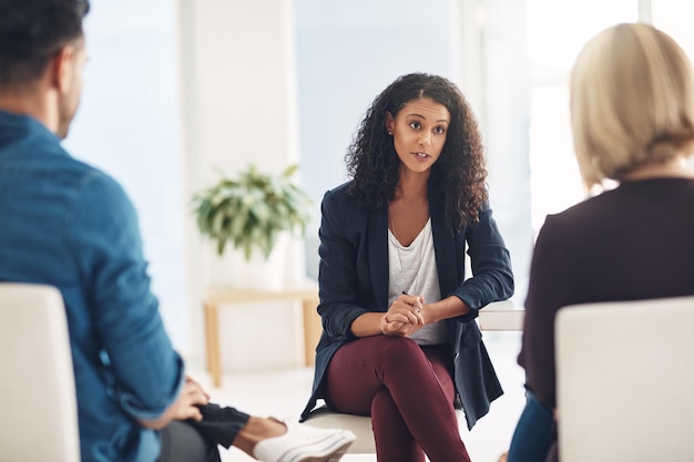 Photo and how does that make you feel. shot of a young therapist speaking to a couple during a counseling session.