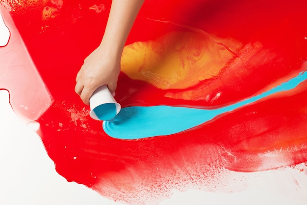 Foto come realizzare la pittura acrilica. lavori in corso. mano femminile che tiene un bicchiere di plastica con vernice blu.