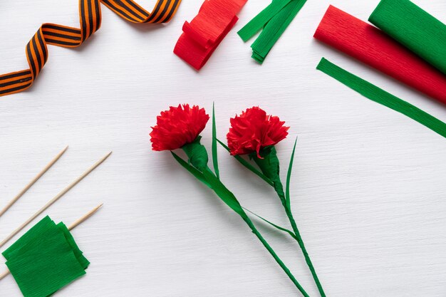 Foto come fare il fiore del garofano a casa. mani che fanno garofano rosso per il giorno della vittoria 9 maggio. istruzioni passo passo. passaggio 17. il fiore è pronto. progetto artistico fai-da-te per bambini. 20apr2020 san pietroburgo russia