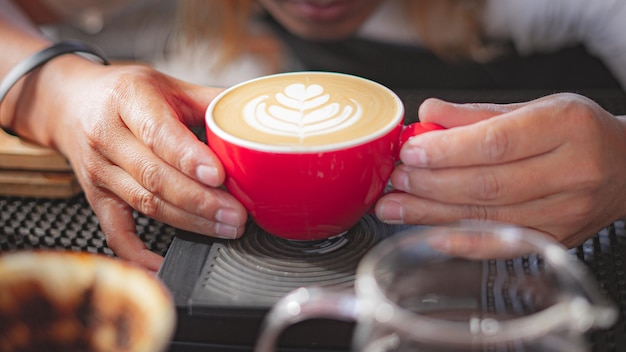 カフェ店内のミルクとコーヒーカップにバリスタがフォーカスしたコーヒーラテアートの作り方