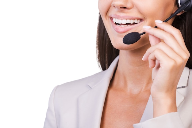 Photo how may i help you? close-up of beautiful young businesswoman adjusting her headset and smiling while isolated on white background