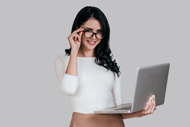 how may i help you? gorgeous young woman in smart casual wear holding laptop 