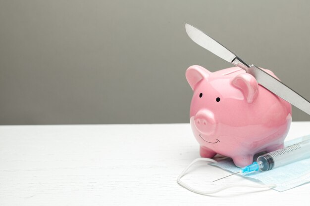 How to save on expensive surgery. Scalpel and syringe near the piggy bank.