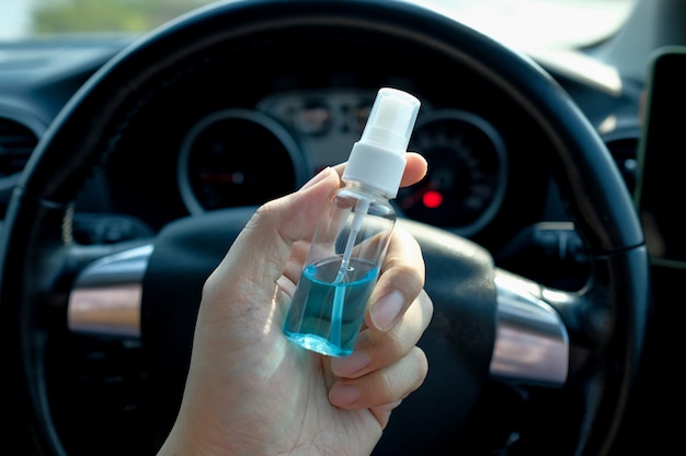 사진 코로나 바이러스 또는 covid-19로부터 안전을 얻는 방법, 운전자는 차에 앉아 있고 그의 손은 알코올 스프레이를 들고 외부에서 나올 수있는 소독 및 소독을합니다.