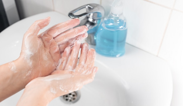 사진 코로나 바이러스, covid-19, 독감의 전염병을 예방하기 위해 손을 씻는 방법. 젊은 여자는 비누로 손을 씻는