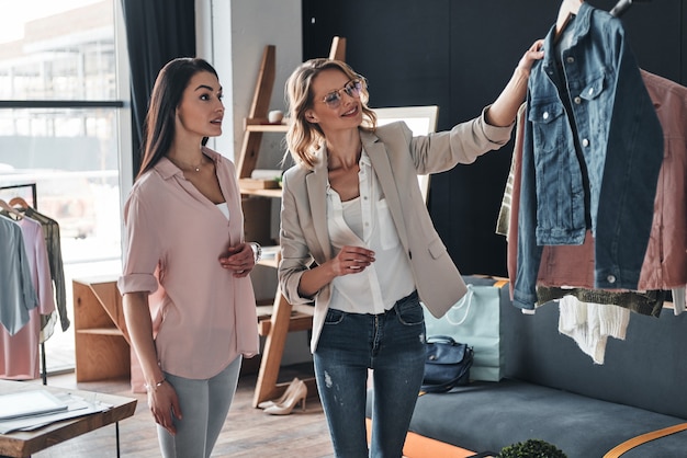 How do you like this one? Beautiful young woman helping to choose clothes to her customer 