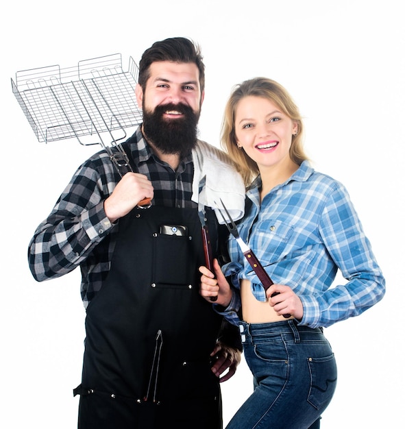 How do you like your steak burnt Couple of man and woman holding barbeque set Barbeque is a cooking method Happy couple having barbeque party Cooking with barbeque grill