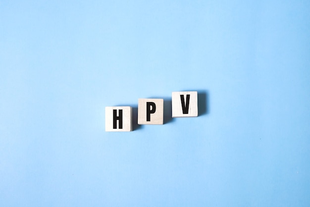 HPV word written on wood block. HPV text on blue for your desing, Top view concept.