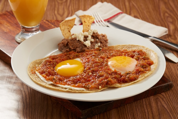 写真 huevos rancheros con salsa picante roja y frijoles refritos desayuno tipico mexicano