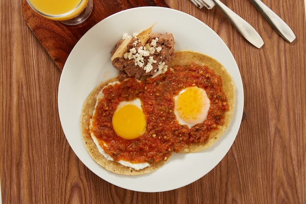 Huevos rancheros con salsa picante roja y frijoles refritos desayuno tipico mexicano