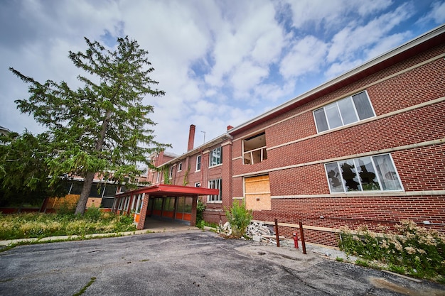 Photo huge abandoned brick hospital building entrance with broken glass and covered windows