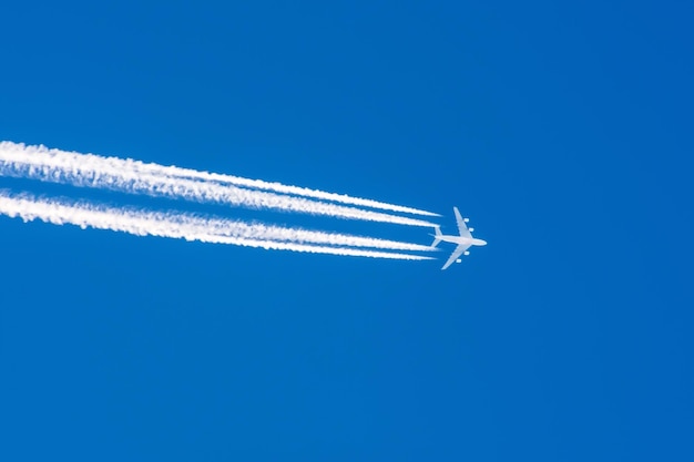 巨大な飛行機の大きな4つのエンジンの航空空港の飛行機雲。