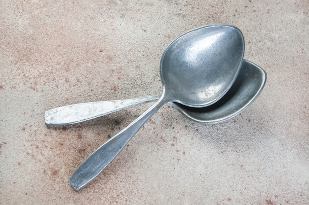 Huge aluminum spoons on concrete background. Copy space for text, food photography props.