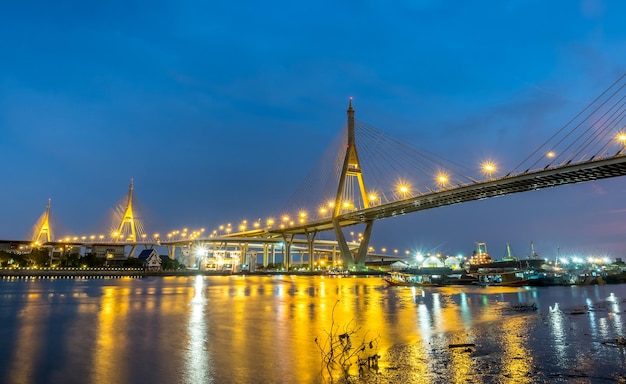 バンコクの夕方の夕暮れのチャオプラヤー川を渡る巨大な橋タイ文字の意味の名前「プーミポン」