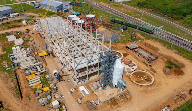 Huge construction site and structures of factory building. Modern factory in the countryside. Huge industrial complex among picturesque green nature