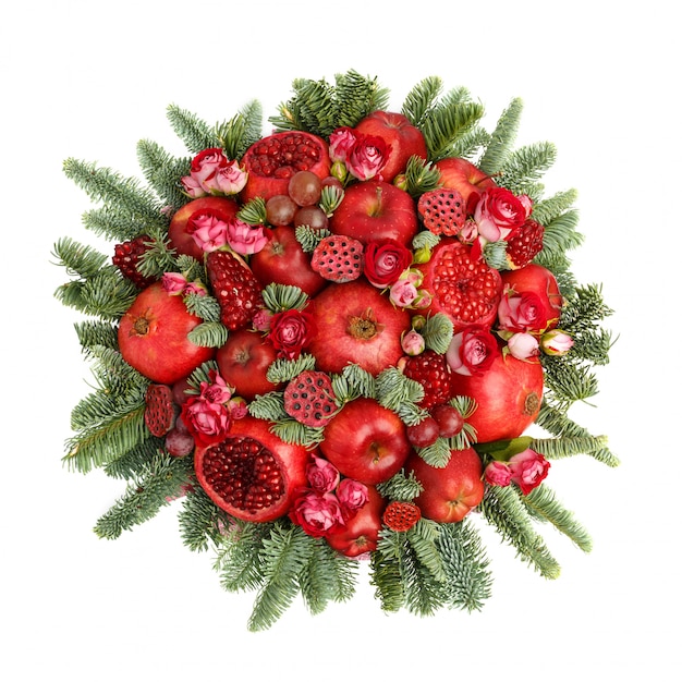 Huge edible fruit bouquet consisting of pomegranates, apples, grapes, rose flowers and fir twigs on white