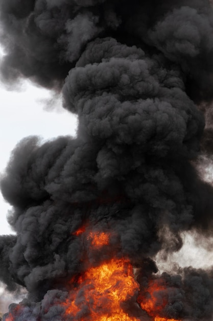 Enormi fiamme di fuoco rosso e nuvole di movimento del cielo coperto di fumo nero